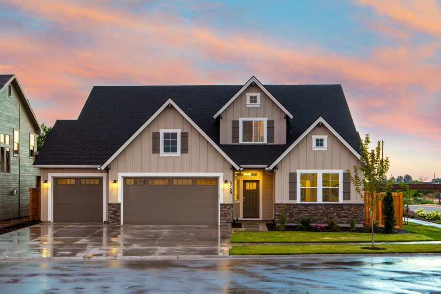 A residential house with a green lawn and some lights on inside